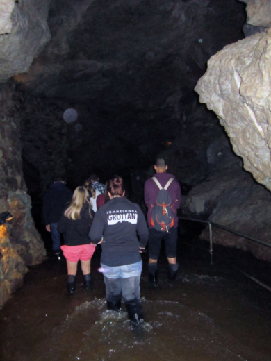 people inside cave with knee-deep water on cave floor